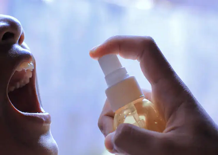 woman squirting perfume in mouth